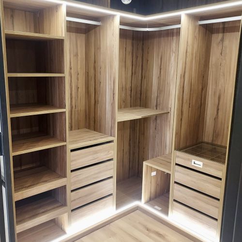 VE99 VESTIDOR EN L CON BALDAS EXTRAIBLES, BALDAS FIJAS, CAJONERAS Y CAJON DIVIDIDO CON TAPA DE CRISTAL. LUCES LED SUPERIORES E INFERIORES